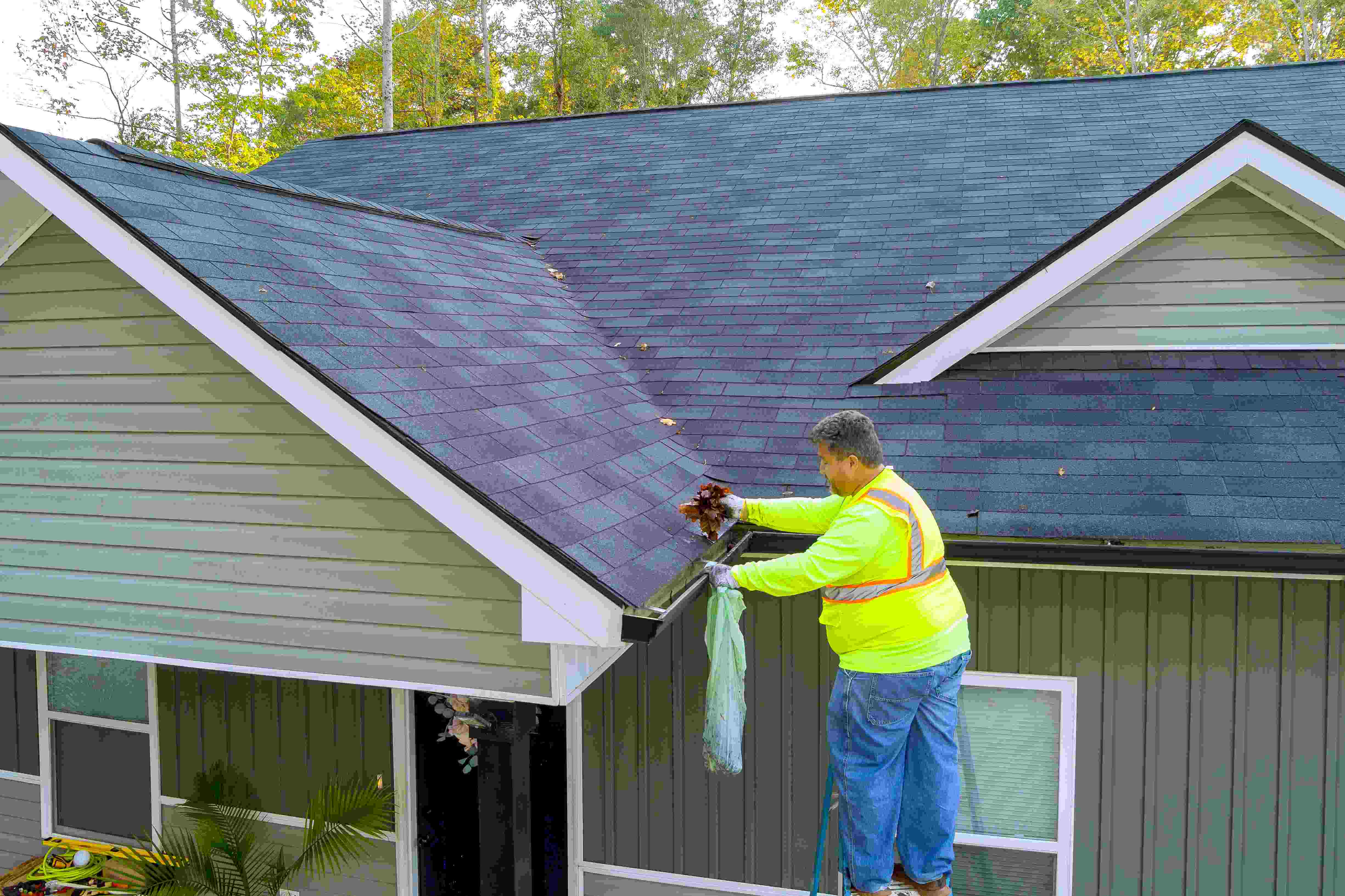 worker-is-cleaning-clogged-roof-gutter-from-dirt